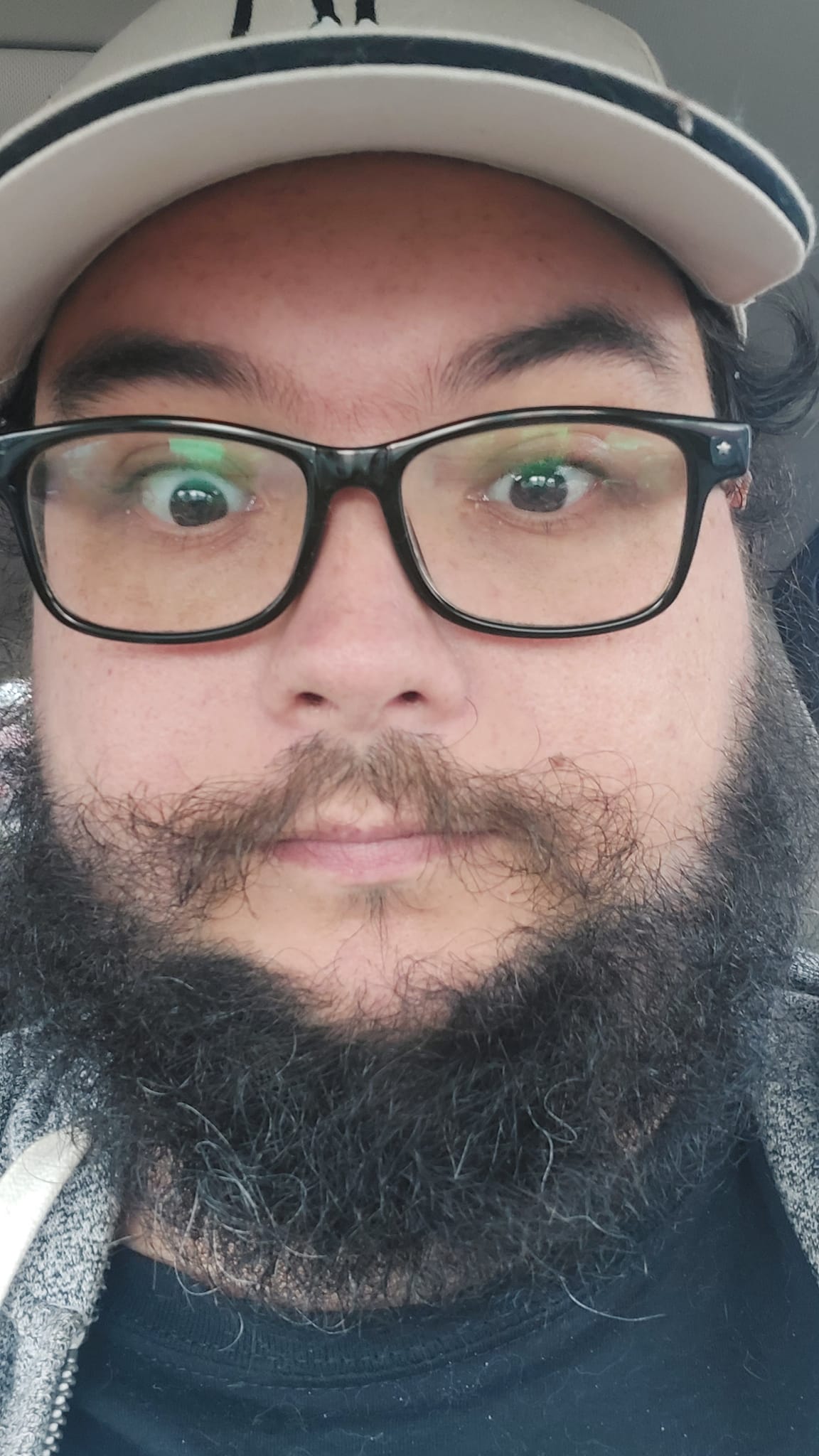 A close up of a man, his beard is as shaggy as before but his moustache is much, much messier than it was before he put on the mask